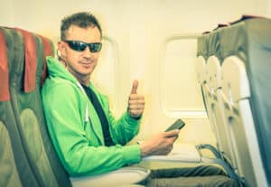 Blog image Young hipster man passenger satisfied with thumbs up inside airplane