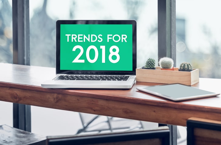 Blog image Trends for 2018 word in laptop computer screen with tablet on wood stood table in at window with blur background