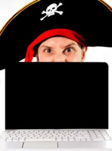 Man in pirate hate behind laptop computer