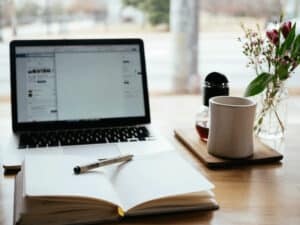 Laptop with notebook and pen on table