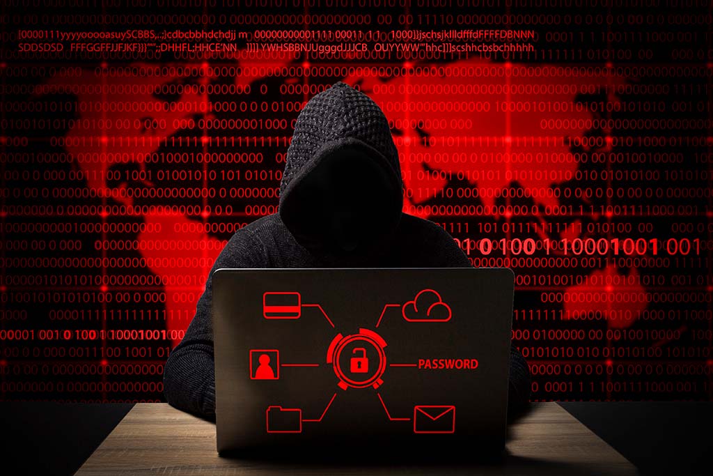 hacker in hoodie on red background - St. Louis cybersecurity