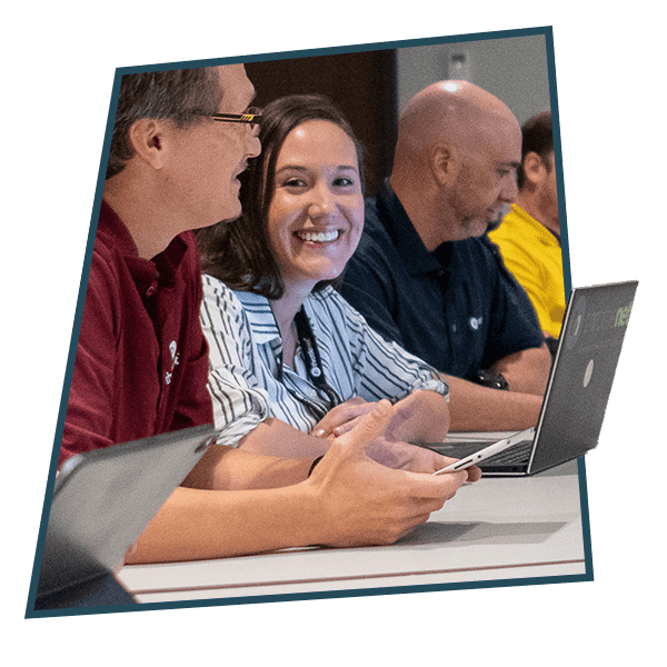 Woman smiling using laptop next to man with cellphone