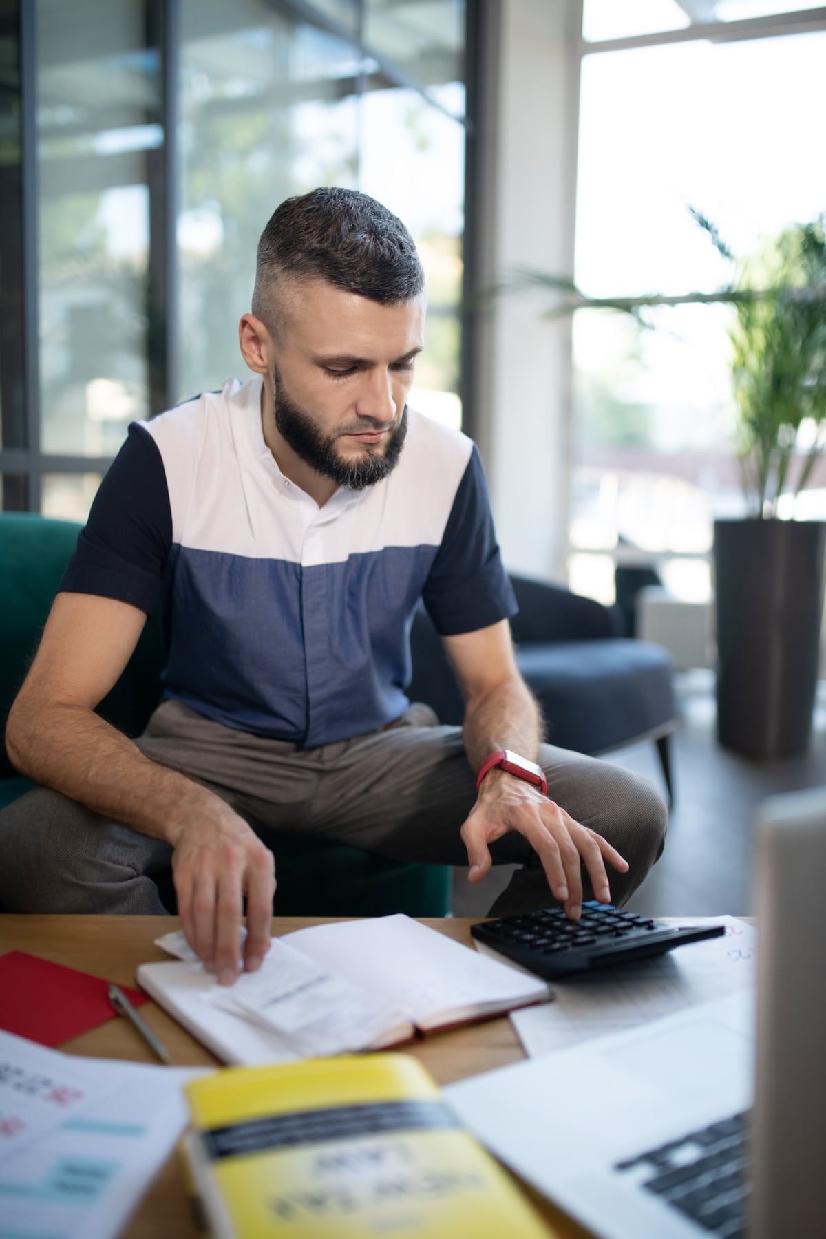 Bearded man using calculator in office setting