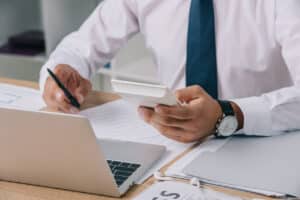 accountant making calculations and practicing accounting cybersecurity workplace with papers and laptop