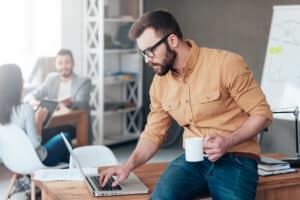 it services professional working on laptop with coffee in hand